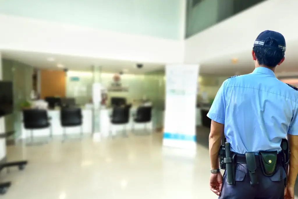 A security guard stands in a modern, bright office lobby.